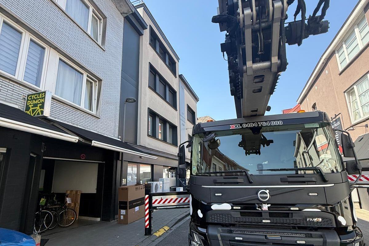 Vrachtwagen met laadkraan tijdens een interventie voor een handelszaak