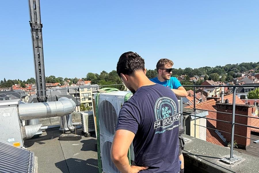 Technici van FM Cooling plaatsen met een kraan een airco-unit op een dak